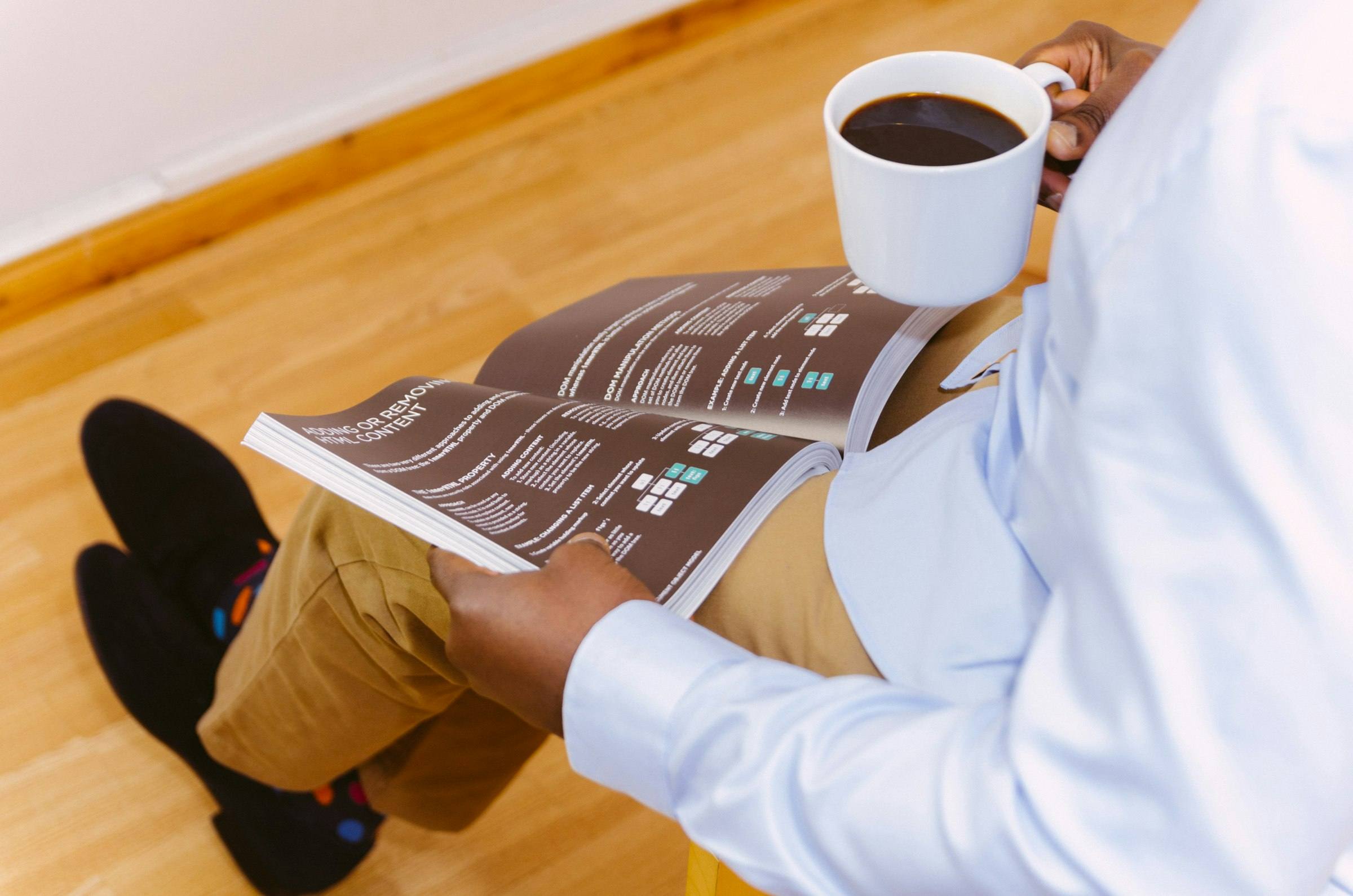 A man reading a magazine with a cup of coffee