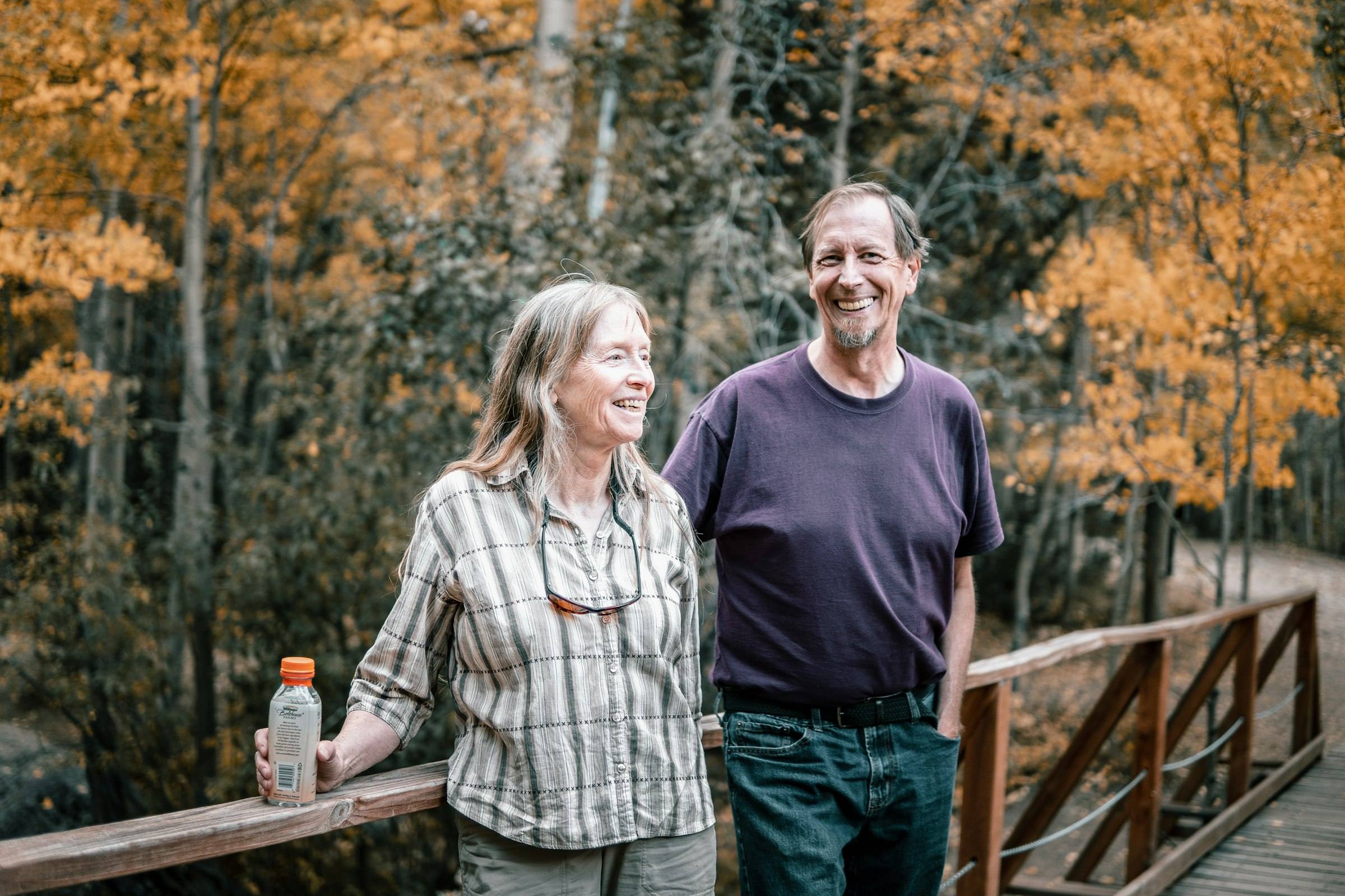 An older couple smiling outdoors on an autumn walk
