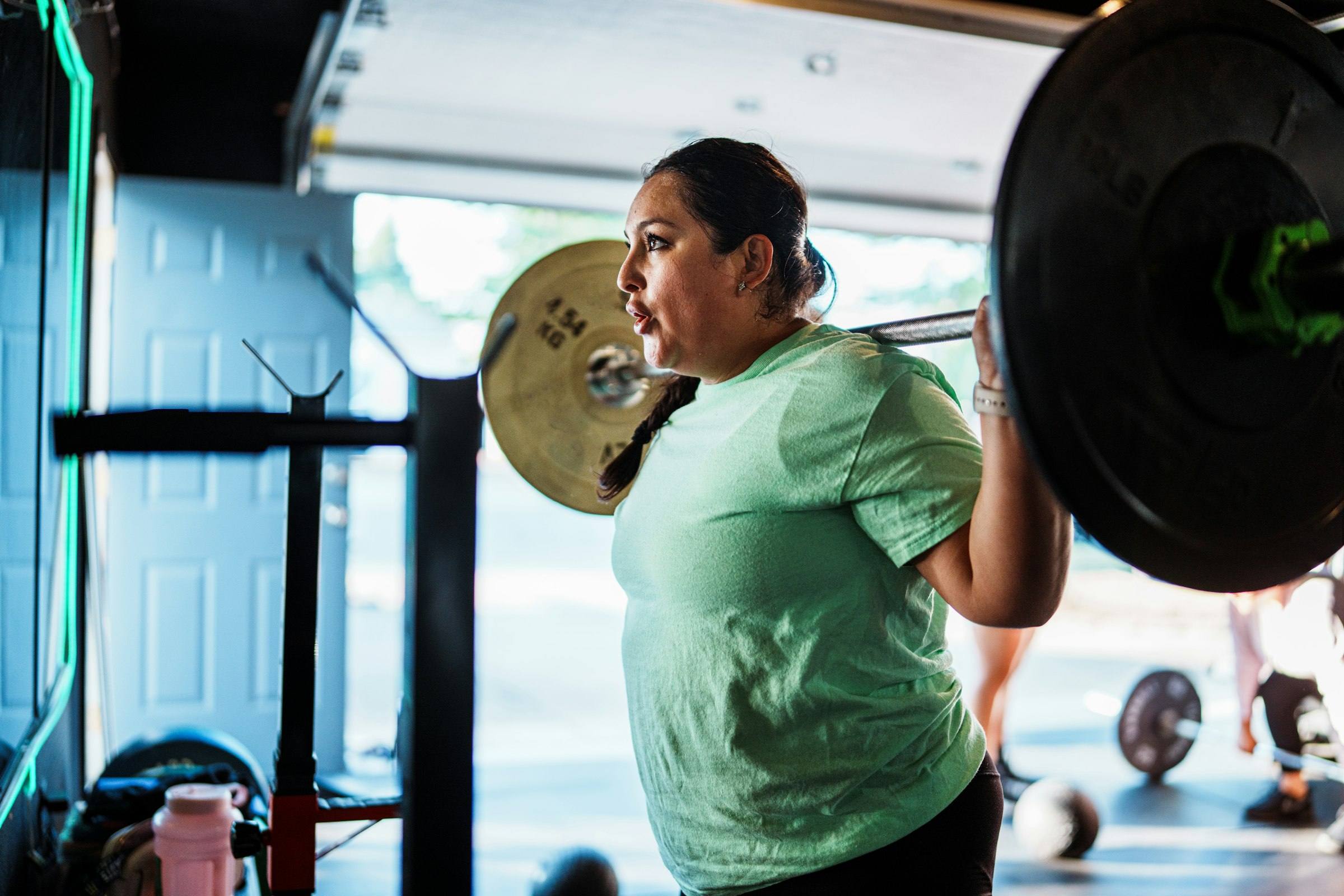 A woman doing a barbell squat in a gym